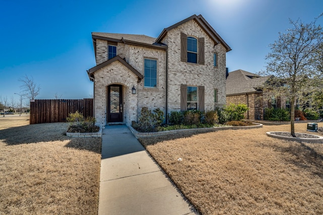 view of front of property featuring brick siding, a front yard, and fence