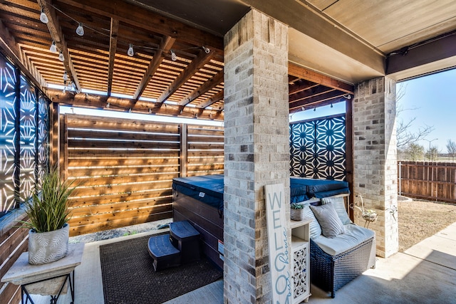 view of patio / terrace featuring a hot tub and fence