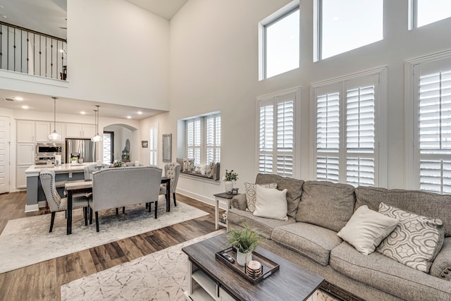 living room featuring dark wood finished floors, recessed lighting, arched walkways, and baseboards