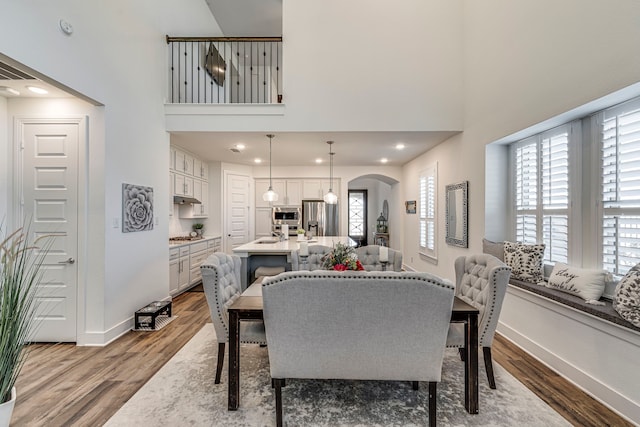 dining area with arched walkways, light wood-type flooring, and a wealth of natural light