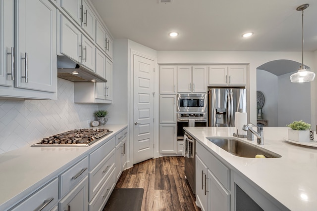 kitchen featuring light countertops, arched walkways, appliances with stainless steel finishes, and a sink