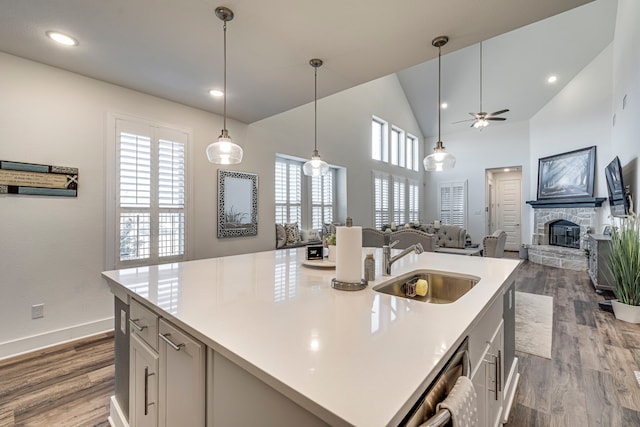 kitchen featuring dark wood finished floors, light countertops, a fireplace, and a sink