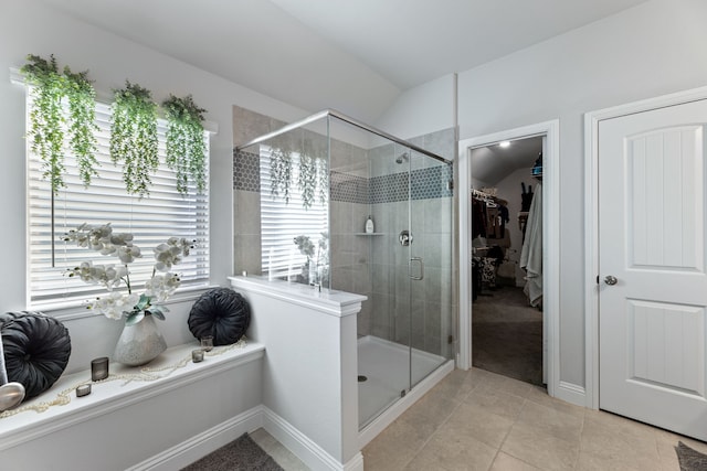 bathroom with a walk in closet, tile patterned floors, baseboards, and a stall shower