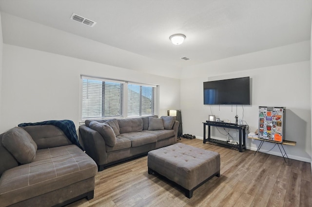 living room featuring visible vents, baseboards, and light wood-style flooring