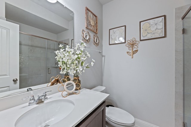 bathroom with a tile shower, toilet, vanity, and baseboards