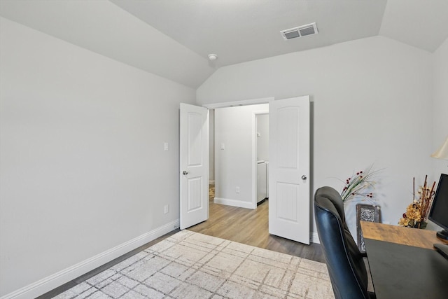 office area featuring visible vents, baseboards, wood finished floors, and vaulted ceiling