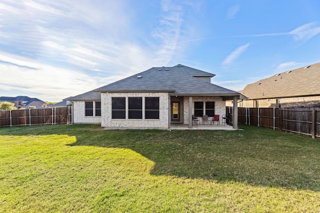 rear view of house featuring a patio, a fenced backyard, a yard, a shingled roof, and brick siding