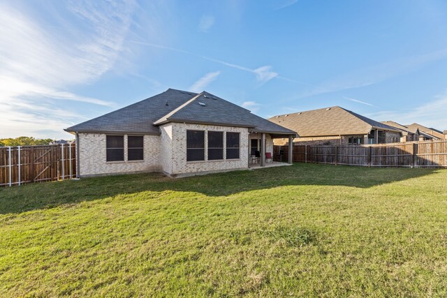 rear view of property with a patio, a yard, a fenced backyard, and brick siding