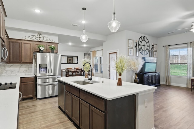 kitchen featuring visible vents, a sink, stainless steel appliances, tasteful backsplash, and light wood-type flooring