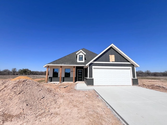 view of front of home with driveway, a garage, and roof with shingles