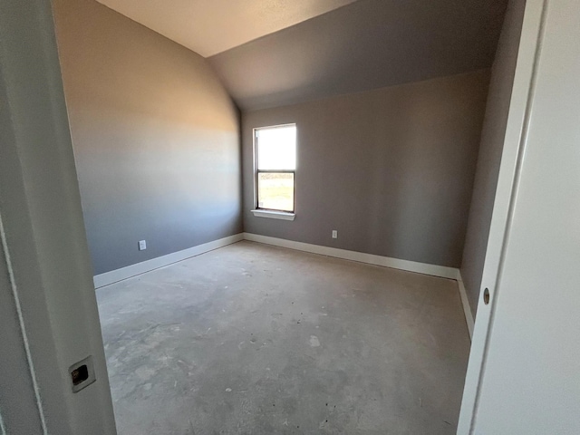 empty room featuring baseboards, lofted ceiling, and concrete flooring