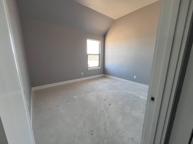 empty room featuring baseboards, lofted ceiling, and concrete floors