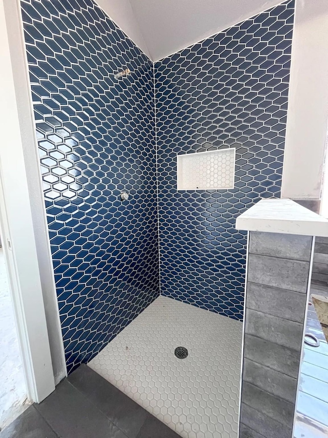 full bathroom with tiled shower, lofted ceiling, and tile patterned flooring