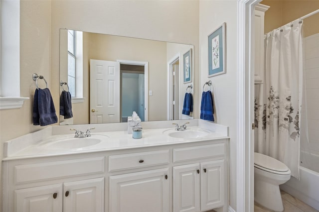 bathroom featuring double vanity, toilet, shower / tub combo, and a sink