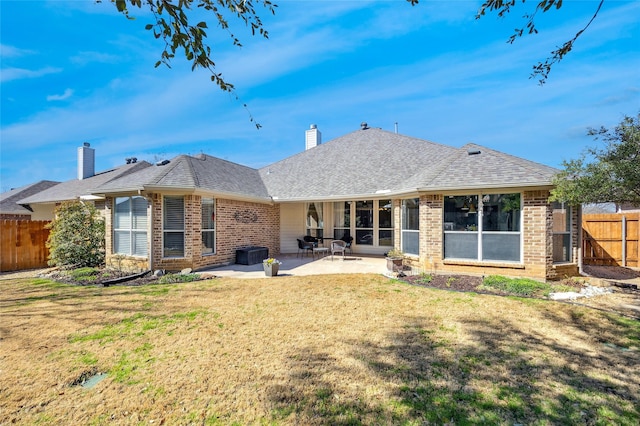 rear view of house featuring a yard, a patio, brick siding, and fence