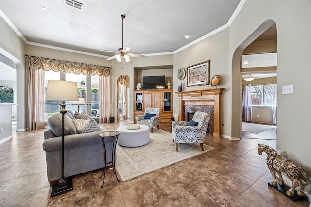 living room with visible vents, arched walkways, crown molding, a premium fireplace, and baseboards