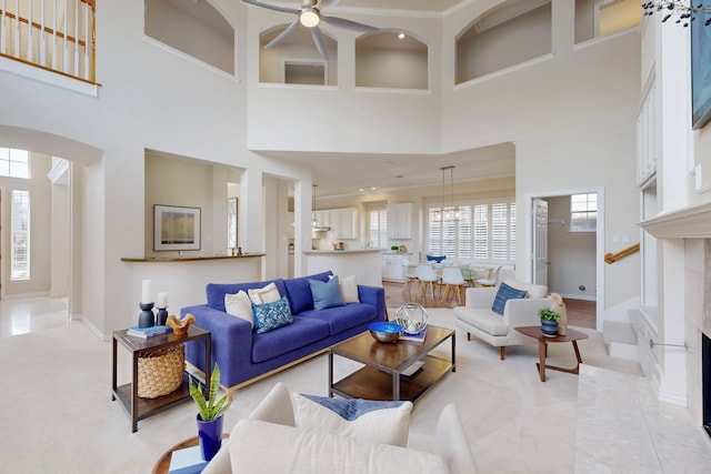 living room with arched walkways, a fireplace, baseboards, and light tile patterned flooring