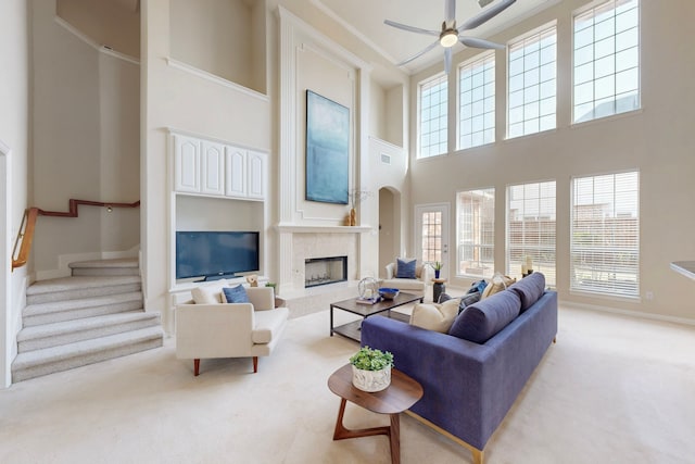 living room featuring a high end fireplace, stairs, ornamental molding, light carpet, and arched walkways