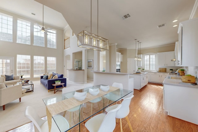 dining space with visible vents, light wood-style flooring, ceiling fan, and ornamental molding