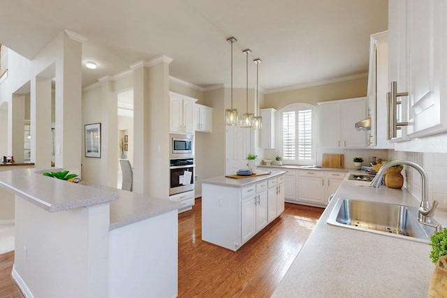 kitchen featuring a sink, a center island, light wood-style floors, appliances with stainless steel finishes, and white cabinets