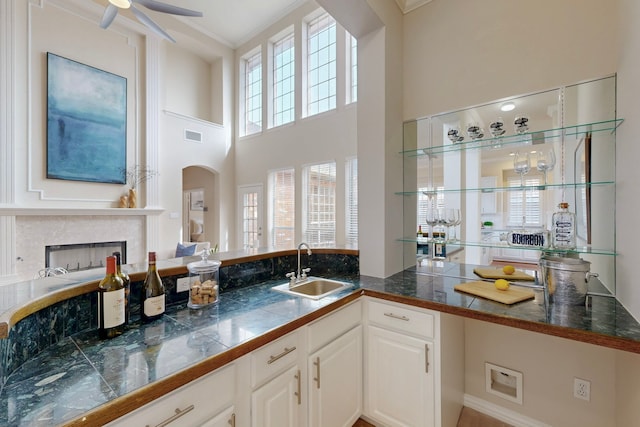 bar with visible vents, ornamental molding, a sink, arched walkways, and a fireplace