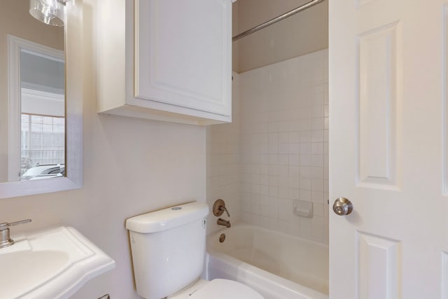 bathroom featuring toilet, shower / bathing tub combination, and a sink