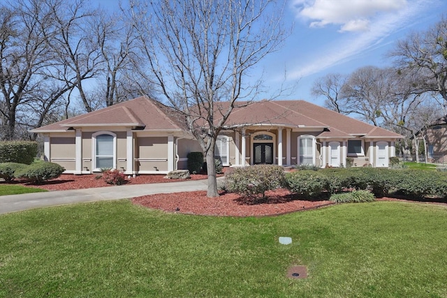 view of front of property with stucco siding, driveway, and a front lawn