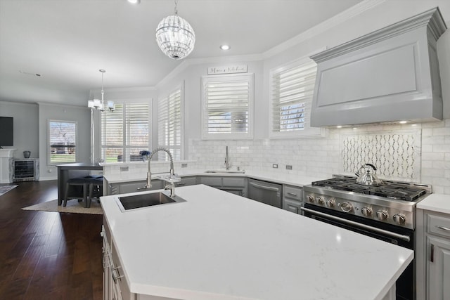 kitchen featuring a notable chandelier, ornamental molding, a sink, a center island, and stainless steel appliances