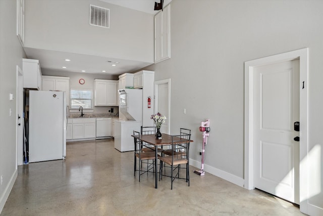 dining area featuring visible vents, finished concrete floors, recessed lighting, baseboards, and a towering ceiling