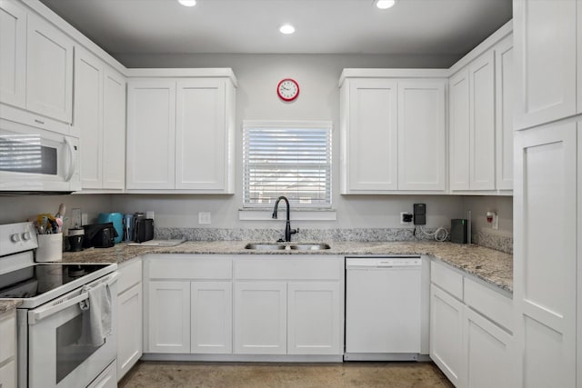 kitchen featuring white appliances, white cabinets, recessed lighting, and a sink