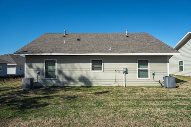 back of house with cooling unit, a shingled roof, and a yard