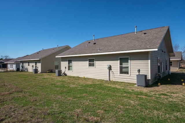 back of property featuring a lawn, central AC, and roof with shingles