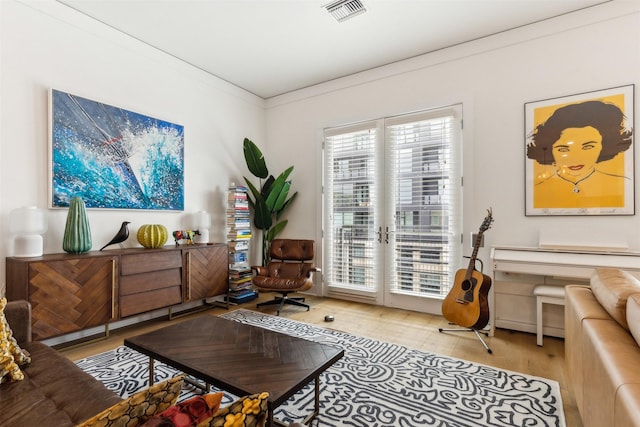 sitting room featuring visible vents, wood finished floors, and ornamental molding