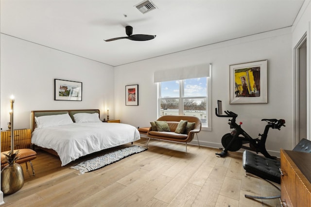 bedroom featuring light wood finished floors, visible vents, baseboards, and ceiling fan