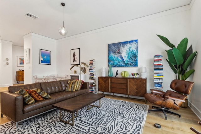 living area with visible vents, wood finished floors, and crown molding