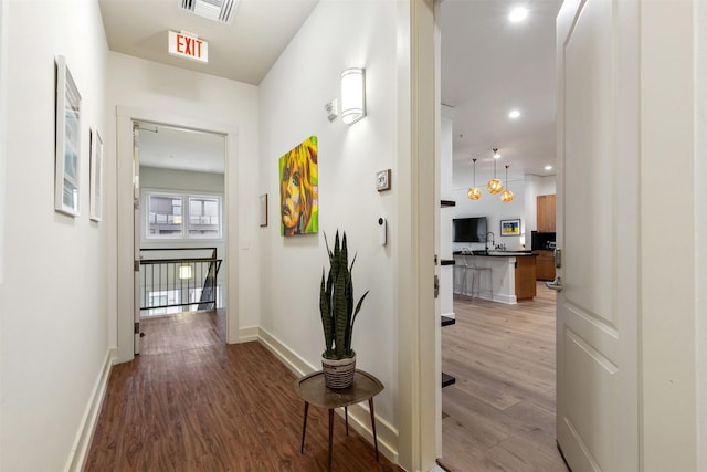 corridor featuring light wood-type flooring, visible vents, baseboards, and recessed lighting