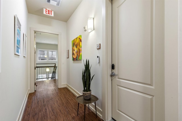 corridor with visible vents, baseboards, and dark wood-style flooring