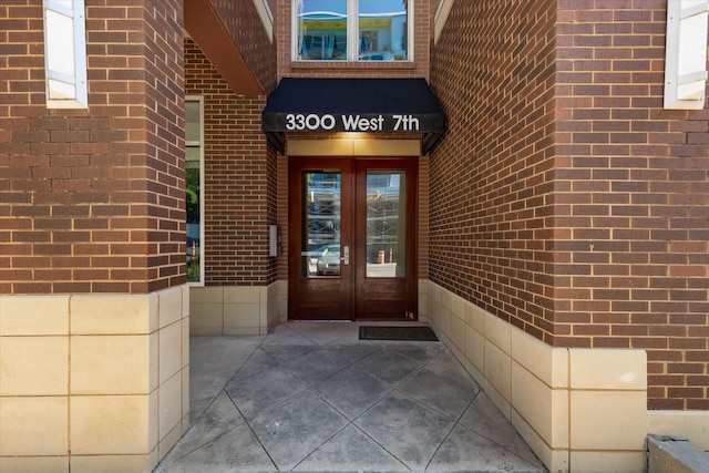 doorway to property featuring french doors and brick siding