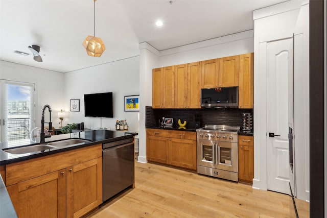 kitchen with dark countertops, visible vents, light wood-style flooring, appliances with stainless steel finishes, and a sink