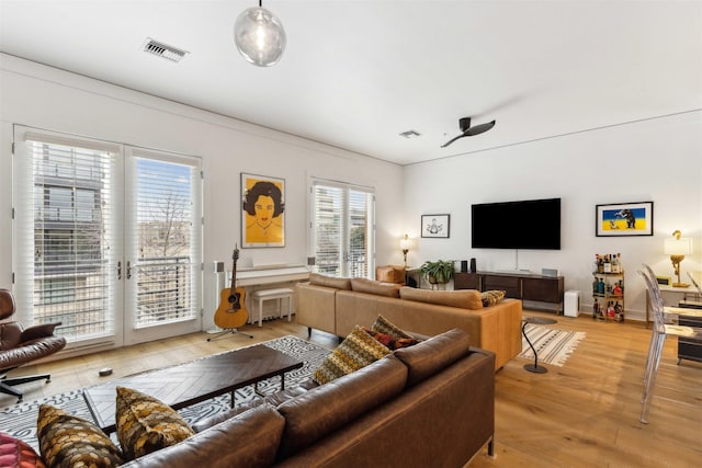 living room featuring light wood-style flooring, french doors, visible vents, and baseboards