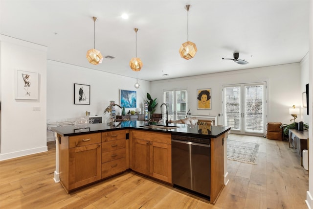 kitchen featuring dark countertops, open floor plan, dishwasher, light wood-type flooring, and a sink