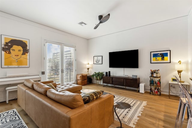 living area with baseboards, visible vents, light wood finished floors, and ceiling fan