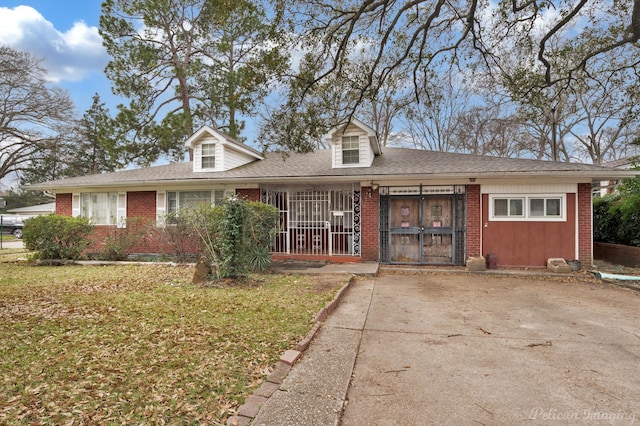 view of front of home featuring brick siding, roof with shingles, and a front lawn