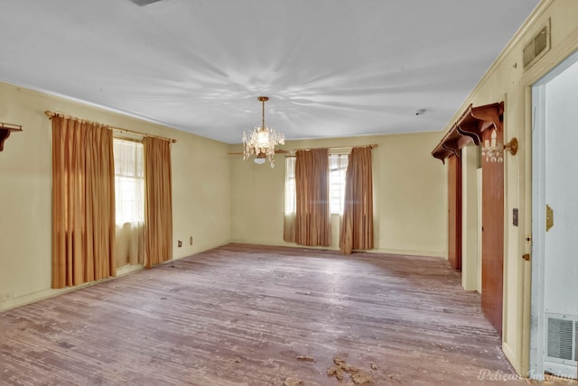 unfurnished room featuring a notable chandelier, visible vents, and wood finished floors