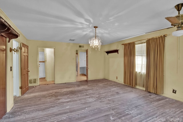 spare room with visible vents, a notable chandelier, and wood finished floors