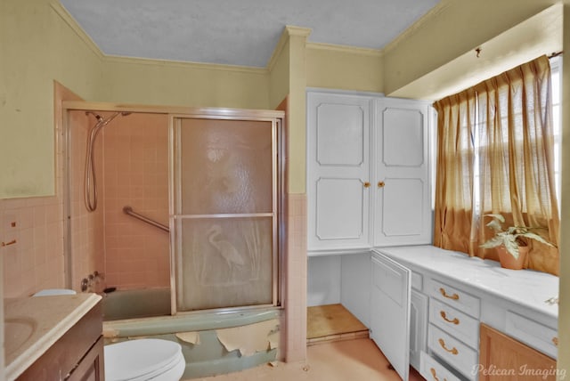 full bathroom featuring vanity, ornamental molding, toilet, and enclosed tub / shower combo