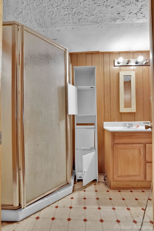 bathroom with vanity, a shower stall, wooden walls, and tile patterned floors