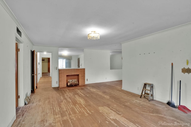 unfurnished living room with a brick fireplace, crown molding, and wood finished floors