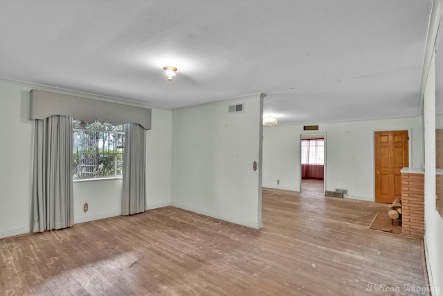 empty room featuring crown molding, wood finished floors, visible vents, and baseboards