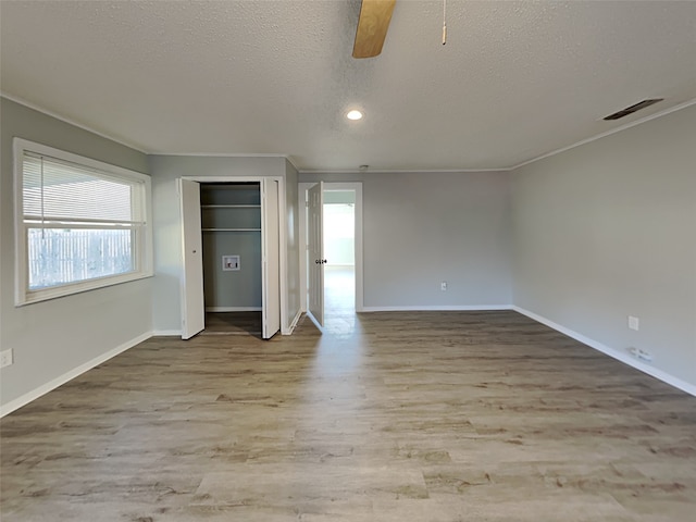 unfurnished bedroom with a ceiling fan, wood finished floors, visible vents, and a textured ceiling